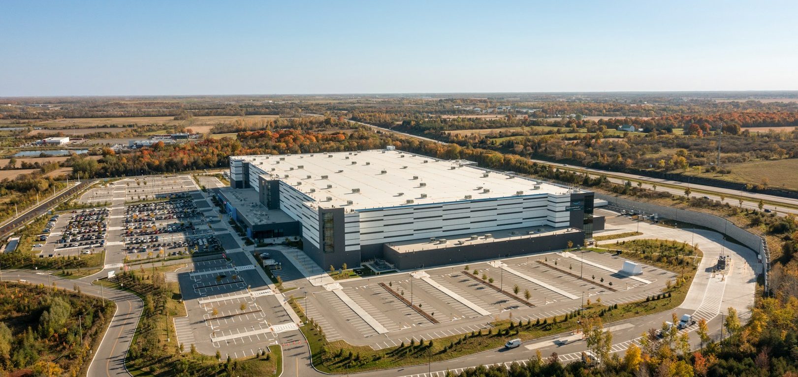 A large industrial building surrounded by parking lots and trees.